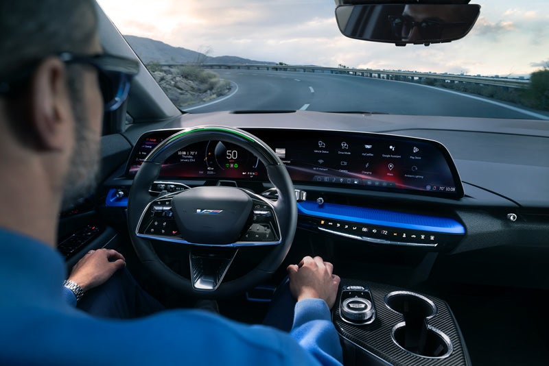 Front View of the 2026 OPTIQ-V Driving Through the Dusk Utilizing its Headlights | Village Cadillac of Homosassa in Homosassa FL